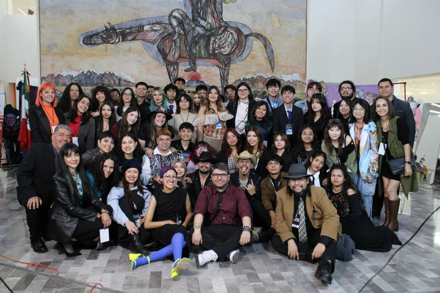 Grupo de estudiantes durante una visita cultural frente a un mural