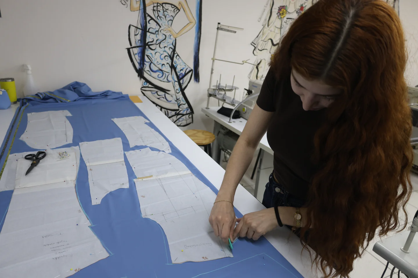 Estudiante trabaja con moldes y textiles sobre una mesa de corte