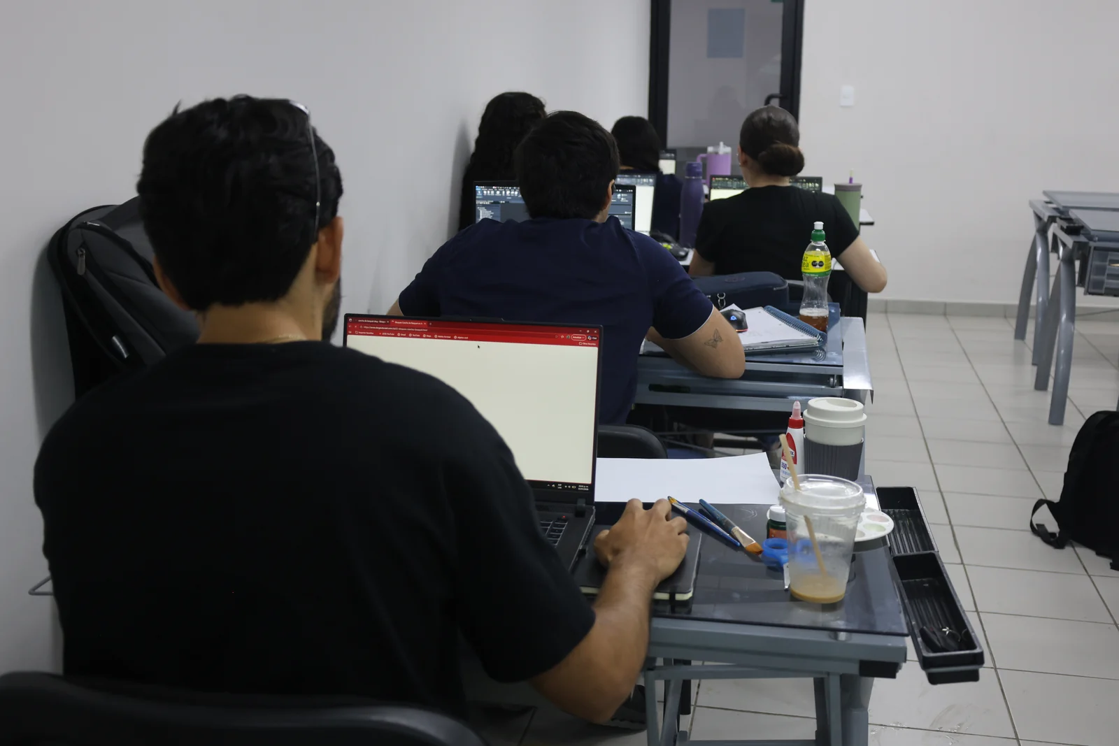 Estudiantes trabajan con computadoras portátiles en el aula