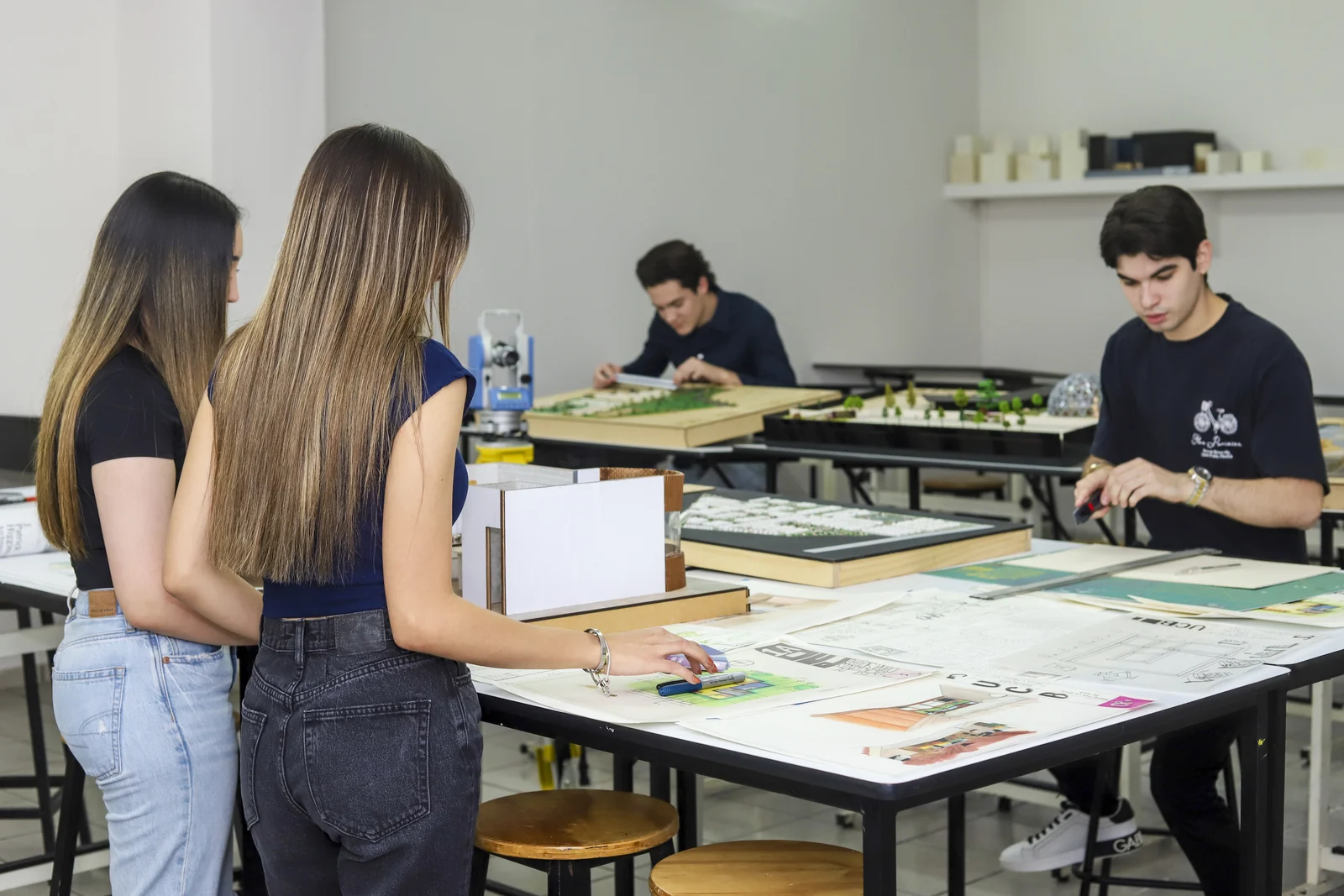 Estudiantes revisan planos y trabajan en mesas del taller de arquitectura