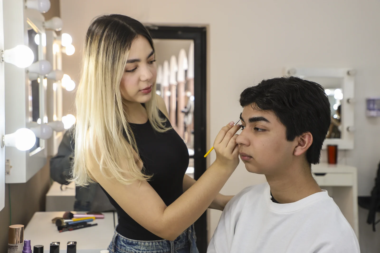 Estudiante realiza una práctica de maquillaje con un compañero