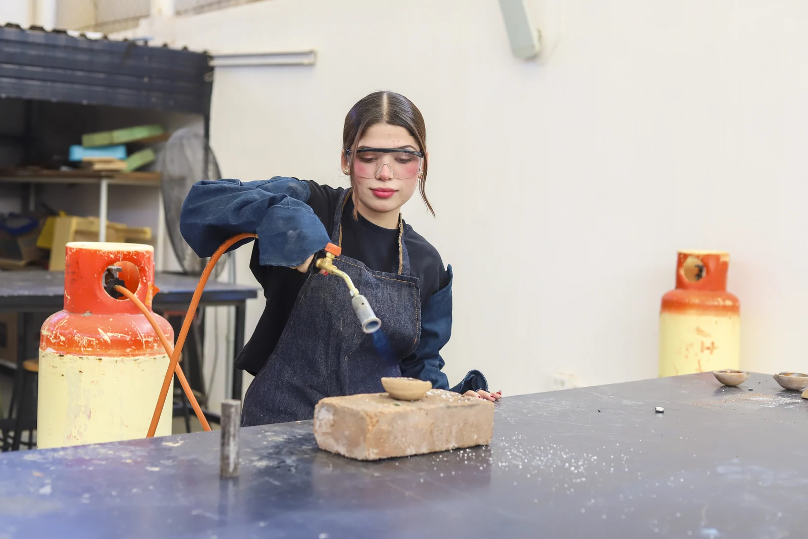 Estudiante trabaja una pieza de metal con herramientas en el taller industrial